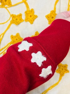 A red sweatshirt sleeve with crochet stars on the cuff.